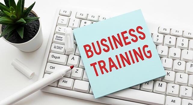 de cerca de un ligero azul pegajoso Nota con el palabras negocio formación en rojo metido en un blanco computadora teclado en un brillante oficina ajuste transporte un mensaje de profesional desarrollo y aprendizaje foto