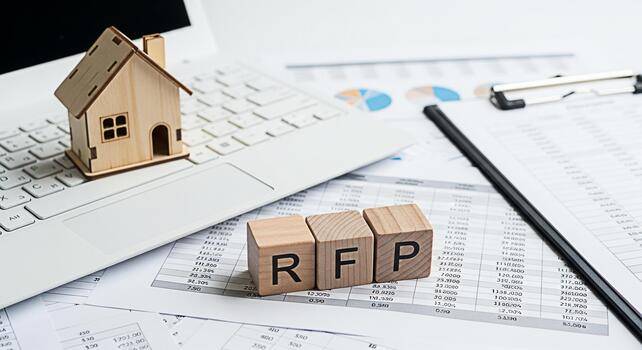 Wooden house model and RFP blocks on a laptop in a bright office setting symbolizing real estate investment opportunities and the process of requesting proposals for property development projects photo