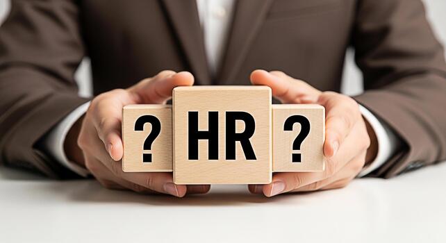 Professional holding wooden blocks with HR and question marks on a white table representing human resources challenges and uncertainty in a modern business environment conveying a sense of inquiry photo