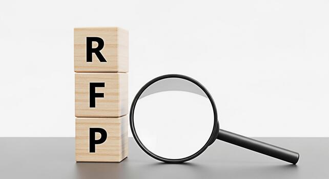 Wooden blocks displaying RFP are examined with a magnifying glass on a sleek gray surface against a clean white background symbolizing a detailed review and analysis of the request for proposal proces photo