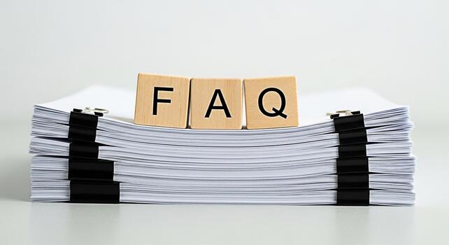 Wooden FAQ blocks resting on a stack of paperwork with binder clips in a bright office setting representing frequently asked questions and information resources for customer support and business solut photo