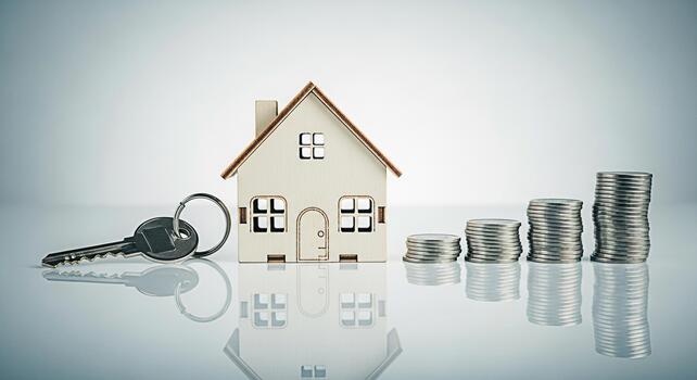 Wooden house model with key and stacks of coins on a reflective surface symbolizing investment and financial growth for home ownership in a bright minimalist setting conveying a sense of security photo