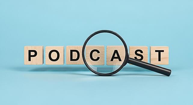 Magnifying glass focusing on wooden blocks spelling PODCAST on a light blue background representing the concept of audio content discovery and the importance of search engine optimization for podcast photo