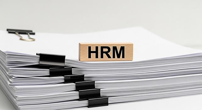 HRM wooden block resting on a stack of paperwork in a bright office setting symbolizing human resources management and efficient document handling for organizational success photo
