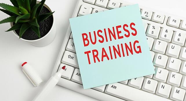 Business training message on a sticky note placed on a white computer keyboard in a bright office environment promoting professional development and skill enhancement for career success photo