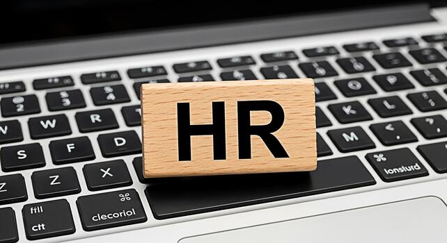Wooden HR block resting on a modern laptop keyboard symbolizing human resources management in a digital environment conveying a professional and organized approach to workforce management photo