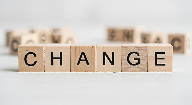 Wooden blocks spelling CHANGE on a white surface symbolizing transformation and progress set against a blurred background of other blocks creating a sense of opportunity and new beginnings in a bright photo