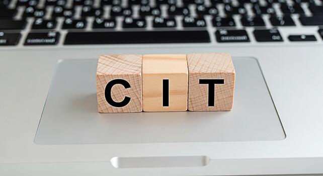 Wooden blocks spelling CIT resting on a laptop touchpad in a bright office environment symbolizing computer information technology and innovation showcasing modern workplace and digital transformation photo