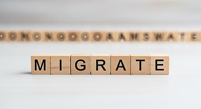 Wooden blocks spelling MIGRATE on a white surface suggesting relocation moving or immigration in a clean minimalist setting conveying a sense of change and new beginnings photo