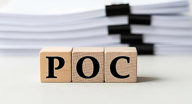 Wooden blocks spelling POC on a desk in front of a stack of papers representing Proof of Concept in a business environment conveying a sense of validation and feasibility assessment photo