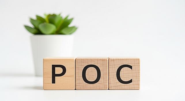 Wooden blocks displaying POC on a white table with a small potted plant in the background representing a Proof of Concept in a clean and minimalist setting conveying clarity and focus photo