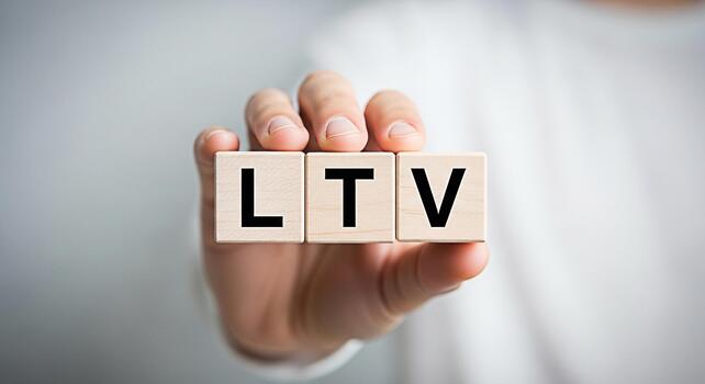 Closeup of a hand holding wooden blocks displaying the letters LTV against a blurred background representing the concept of Lifetime Value and its importance in business and marketing strategies photo