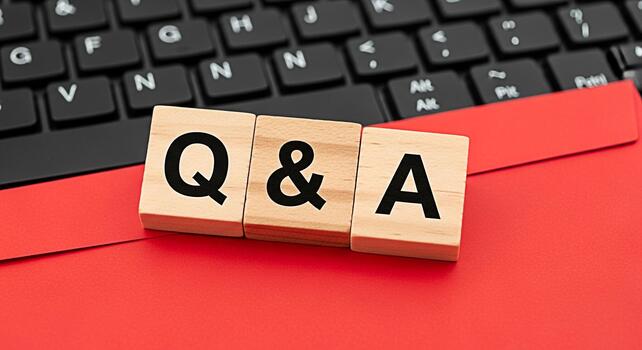 Wooden blocks spelling QA resting on a red surface in front of a computer keyboard representing questions and answers knowledge sharing and information retrieval in a digital environment photo