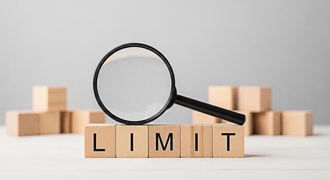 Magnifying glass focusing on the word LIMIT spelled out with wooden blocks on a white table representing boundaries restrictions and the importance of setting limits in business and personal life photo