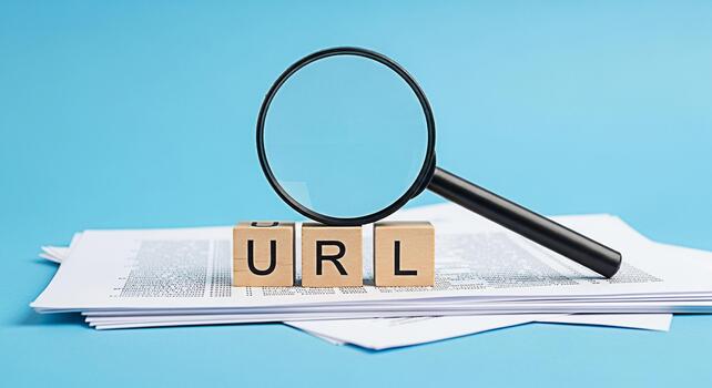 Magnifying glass inspecting URL wooden blocks on a stack of documents against a blue background symbolizing website analysis and search engine optimization for online presence and information discover photo