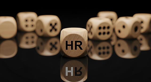 Wooden dice displaying HR in a dark reflective setting symbolizing human resources and strategic decisionmaking within a company fostering a sense of planning and organizational structure photo