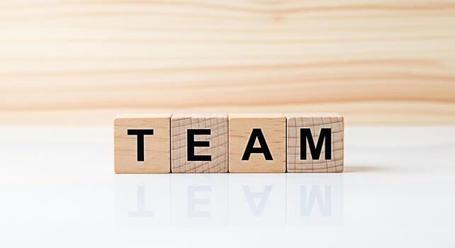 Wooden blocks spelling TEAM on a white reflective surface against a light wood background symbolizing collaboration unity and the importance of teamwork in achieving common goals photo