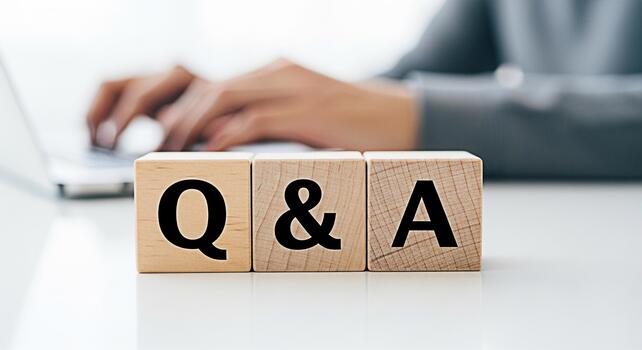 Business professional typing on a laptop with wooden blocks displaying Q A on a white desk representing question and answer sessions knowledge sharing and interactive communication in a corporate sett photo