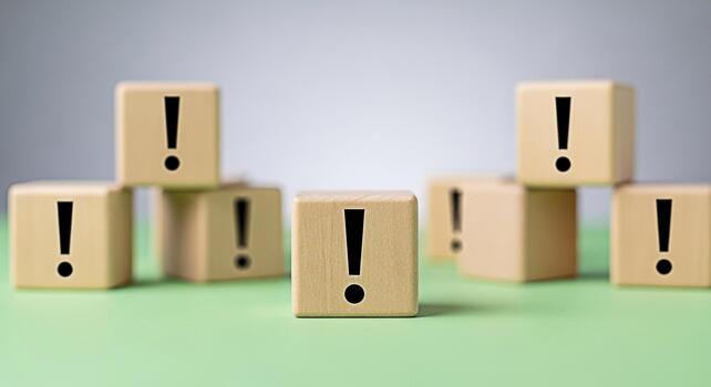 Wooden blocks displaying exclamation points on a green surface symbolizing urgency and importance highlighting a critical message or warning in a simple eyecatching arrangement photo