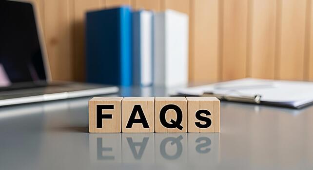 Wooden blocks displaying FAQs on a desk in a modern office setting symbolizing information access and customer support with a laptop and books in the background conveying a sense of clarity and assist photo