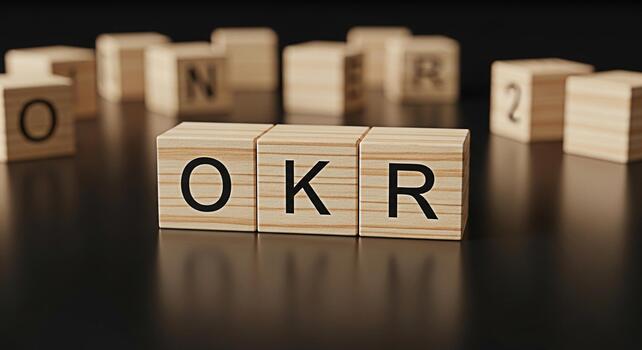 Wooden blocks displaying OKR on a reflective black surface representing objectives and key results in a corporate setting symbolizing strategic planning and goal achievement with a focus on business s photo