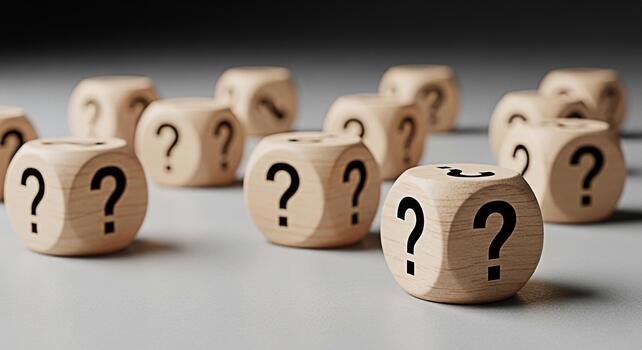 Wooden dice displaying question marks scattered on a gray surface symbolizing uncertainty and the need for answers creating a sense of mystery and intrigue in a minimalist setting photo