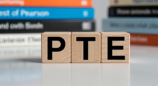 Wooden blocks spelling PTE on a white surface with blurred books in the background representing preparation for the Pearson Test of English showcasing education and learning materials in a studio sett photo