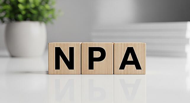 Wooden blocks displaying NPA on a white surface in a bright office setting representing NonPerforming Assets and financial challenges with a clean and modern aesthetic photo