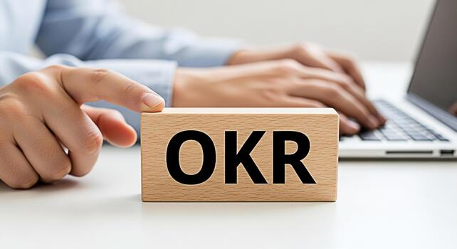 Focused professional using a laptop in a bright office emphasizing the OKR block symbolizing goal setting and achievement in a modern business environment fostering a sense of productivity and strateg photo