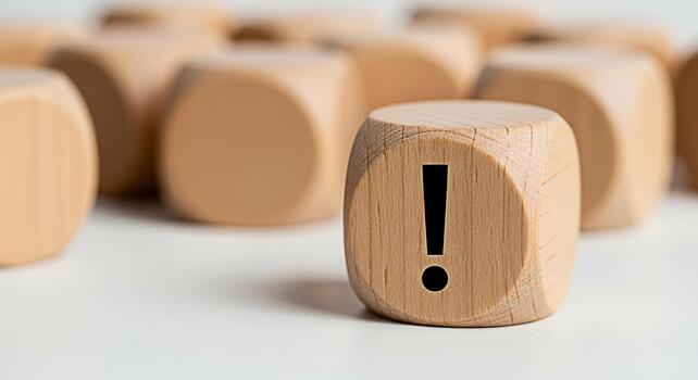 Wooden cube displaying an exclamation mark on a white surface standing out from the blurred background symbolizing attention warning and the importance of problemsolving with a sense of urgency photo
