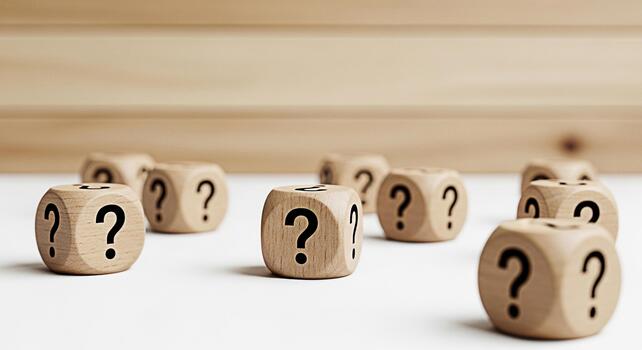 Wooden dice displaying question marks scattered on a white surface against a wood panel background symbolizing uncertainty inquiry and the search for answers in a bright and minimalist setting photo