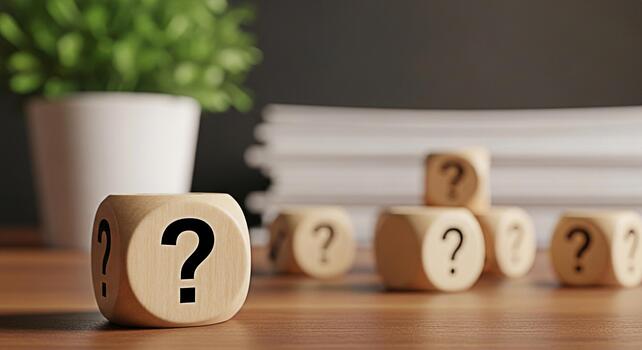 Wooden question mark dice sitting on a desk with a plant and stack of papers representing uncertainty problemsolving and the need for answers in a business or educational setting photo