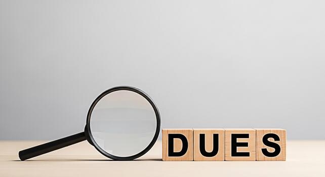 Magnifying glass inspecting wooden blocks spelling DUES on a table symbolizing financial obligations and scrutiny creating a serious and analytical atmosphere for business and personal finance concept photo