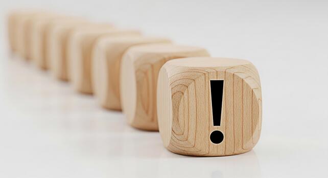 Wooden dice displaying an exclamation mark in a bright studio setting symbolizing attention urgency and the importance of problemsolving and critical thinking for business success photo