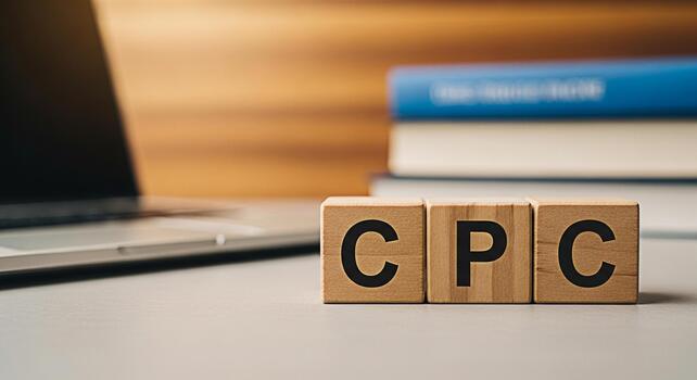 Wooden blocks spelling CPC on a desk with a laptop and books representing cost per click advertising and online marketing strategies in a modern business environment conveying a concept of digital gro photo