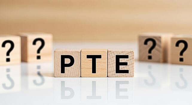 Wooden blocks spelling PTE on a reflective surface surrounded by question marks representing the Pearson Test of English and the uncertainty of exam preparation creating a sense of challenge and antic photo