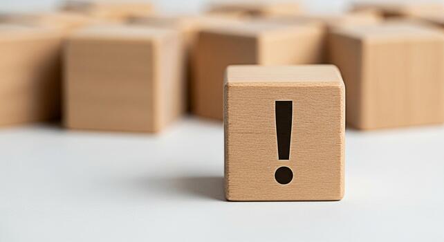 Wooden block displaying an exclamation mark on a white surface standing out among other blocks symbolizing attention warning or important information in a minimalist and clean setting photo