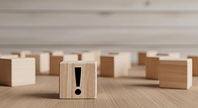 Prominent wooden block displaying an exclamation mark stands out on a wooden surface among similar blocks symbolizing importance attention and a call to action in a minimalist setting photo