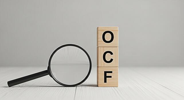 Magnifying glass inspecting wooden blocks spelling OCF on a white wooden surface representing operational cash flow analysis and financial transparency in a clean minimalist setting photo