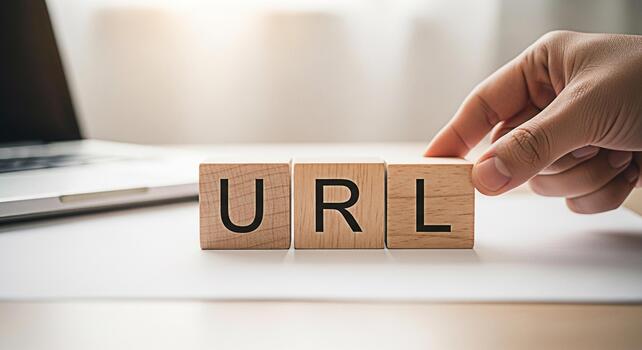 Hand arranging wooden blocks spelling URL on a white desk with a laptop symbolizing website address management and online presence with a focus on clarity and organized information photo
