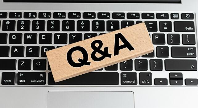 Wooden block displaying QA resting on a silver laptop keyboard symbolizing information exchange and problemsolving in a modern digital environment fostering a sense of clarity and knowledge photo