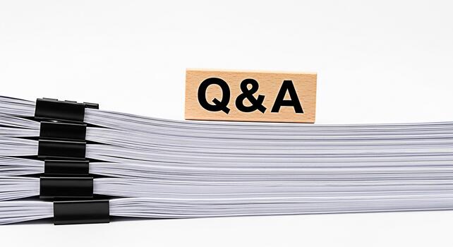 Stack of white papers with black clips and a wooden block displaying QA on a white background representing information knowledge and the importance of questions and answers in business and education photo