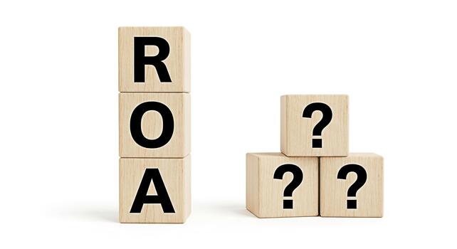 Wooden blocks displaying ROA and question marks on a white background representing financial uncertainty and the need to understand Return on Assets in a clear and concise manner photo