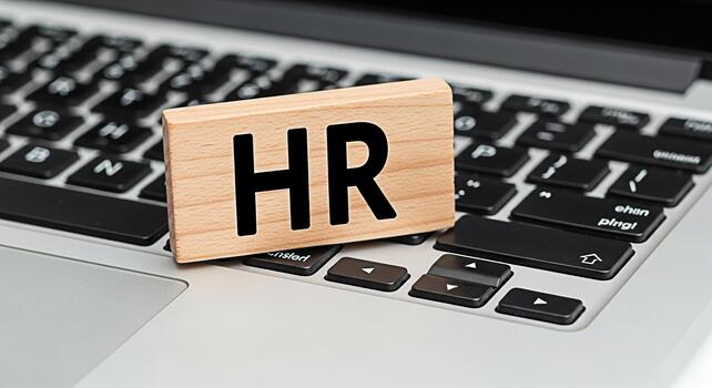 Wooden block with HR placed on a laptop keyboard in a bright office setting symbolizing human resources management recruitment and the importance of people in a modern business environment photo
