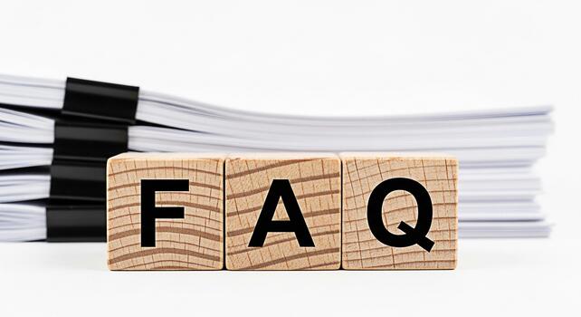 Wooden blocks displaying FAQ with a stack of papers in the background on a white surface representing frequently asked questions and information resources in a clean and organized setting photo