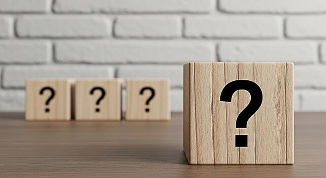 Wooden blocks displaying question marks on a wooden table against a white brick wall representing uncertainty inquiry and the search for answers in a clean and minimalist setting photo