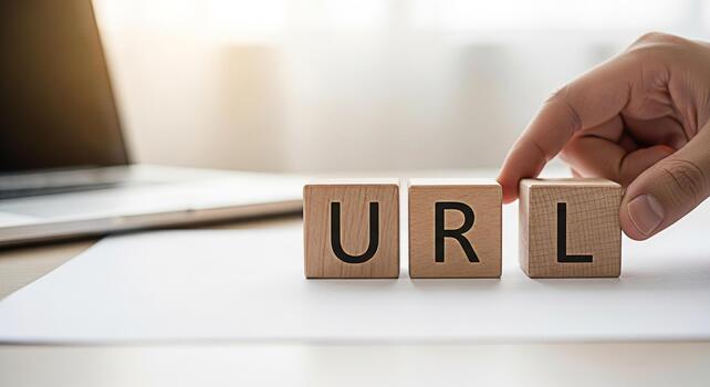 mano arreglando de madera bloques ortografía url en un brillante escritorio con un ordenador portátil simbolizando sitio web habla a administración y en línea presencia en un moderno oficina ambiente transporte un sentido de controlar y digi foto
