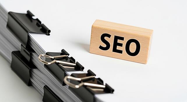 Stack of documents secured with binder clips and a wooden block displaying SEO on a white surface representing the importance of search engine optimization for business success and online visibility photo