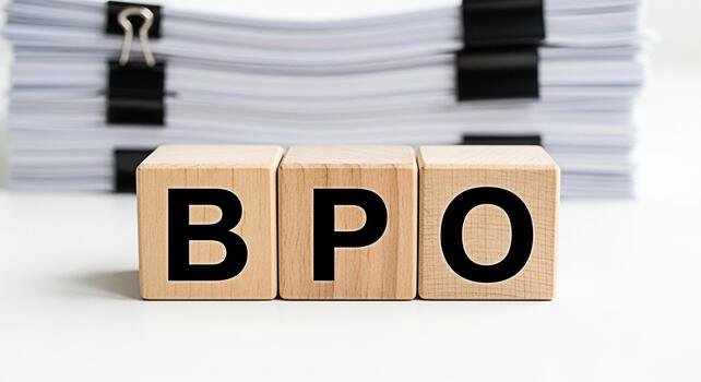 Wooden blocks displaying BPO on a white surface with a stack of papers in the background representing business process outsourcing and efficient document management in a corporate setting photo