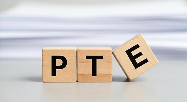 Wooden blocks spelling PTE on a gray surface representing the Pearson Test of English suggesting preparation and success in English language proficiency in an educational setting photo